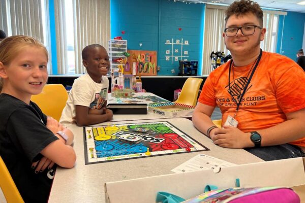 Navaeh, Kyrie, and Alex play a board game in the Cadet Room. Alex is a high school student gaining workforce development experience at the Boys & Girls Club.