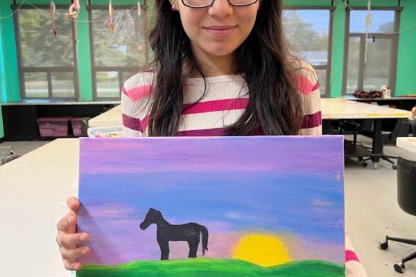 Shila holds art she painted 2022